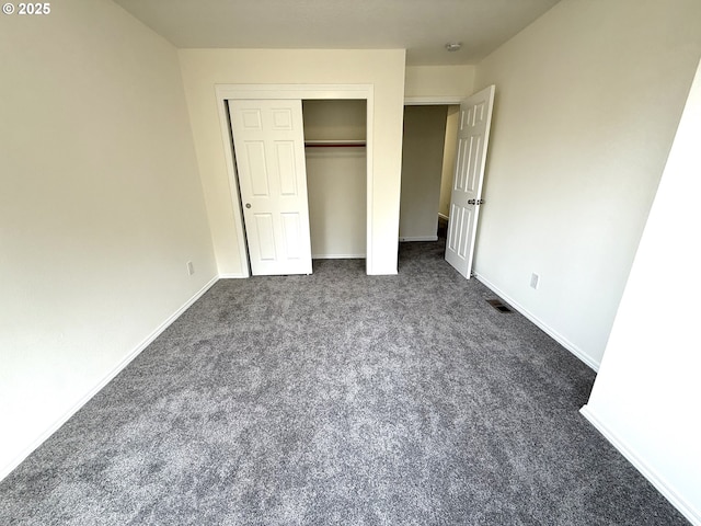 unfurnished bedroom with dark carpet and a closet