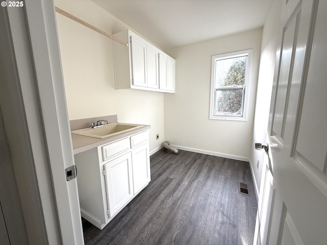 clothes washing area with dark hardwood / wood-style flooring, sink, cabinets, and electric dryer hookup