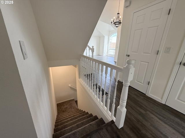 stairway with lofted ceiling, a notable chandelier, and wood-type flooring