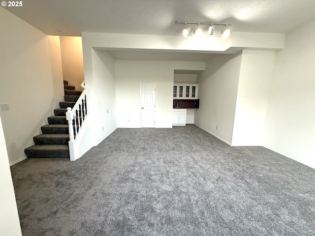 interior space with track lighting, a textured ceiling, and carpet flooring