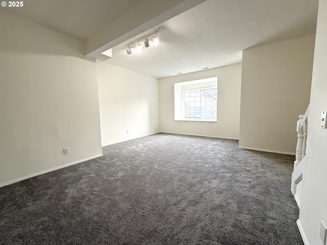 carpeted spare room with track lighting and a textured ceiling