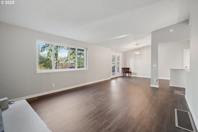 empty room featuring lofted ceiling, dark hardwood / wood-style floors, a chandelier, and a textured ceiling