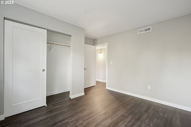 unfurnished bedroom with a closet and dark hardwood / wood-style floors