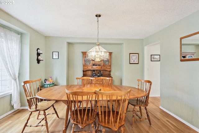 dining room with baseboards, a chandelier, and light wood-style flooring