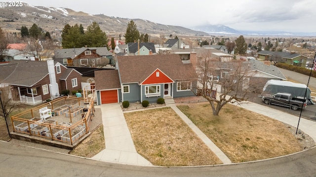 view of front facade with driveway, a mountain view, a residential view, a front yard, and a garage