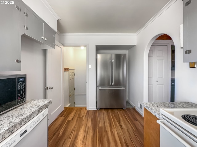 kitchen with appliances with stainless steel finishes, light countertops, light wood-style floors, and ornamental molding