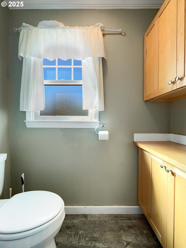 half bath featuring baseboards and toilet