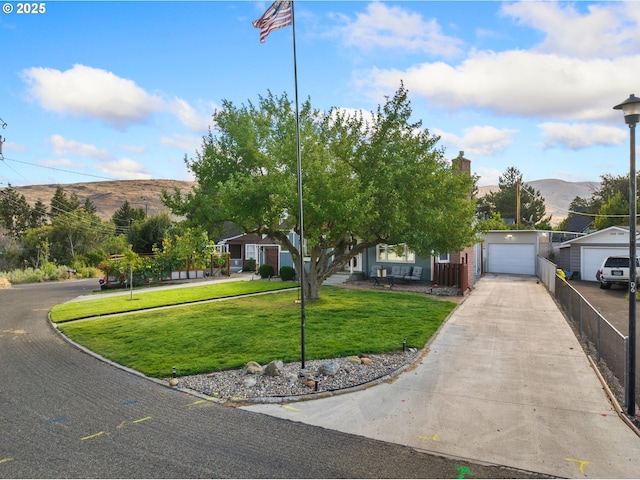 view of front facade featuring a mountain view, fence, a garage, driveway, and a front lawn