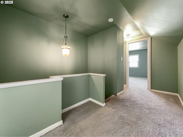 corridor with baseboards, carpet flooring, vaulted ceiling, and an upstairs landing