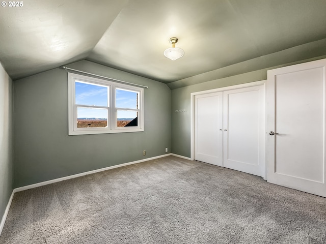 unfurnished bedroom featuring baseboards, carpet floors, lofted ceiling, and a closet