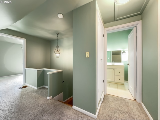 hallway featuring visible vents, carpet, an upstairs landing, and baseboards