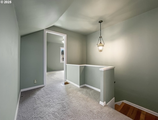 interior space with visible vents, an upstairs landing, vaulted ceiling, baseboards, and carpet