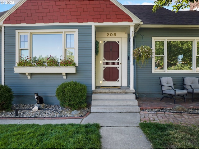 view of exterior entry featuring roof with shingles