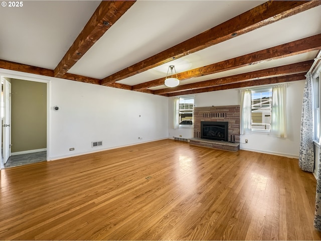 unfurnished living room featuring visible vents, baseboards, beam ceiling, and wood finished floors