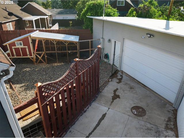 view of patio / terrace featuring an exterior structure, a garage, an outdoor structure, and driveway