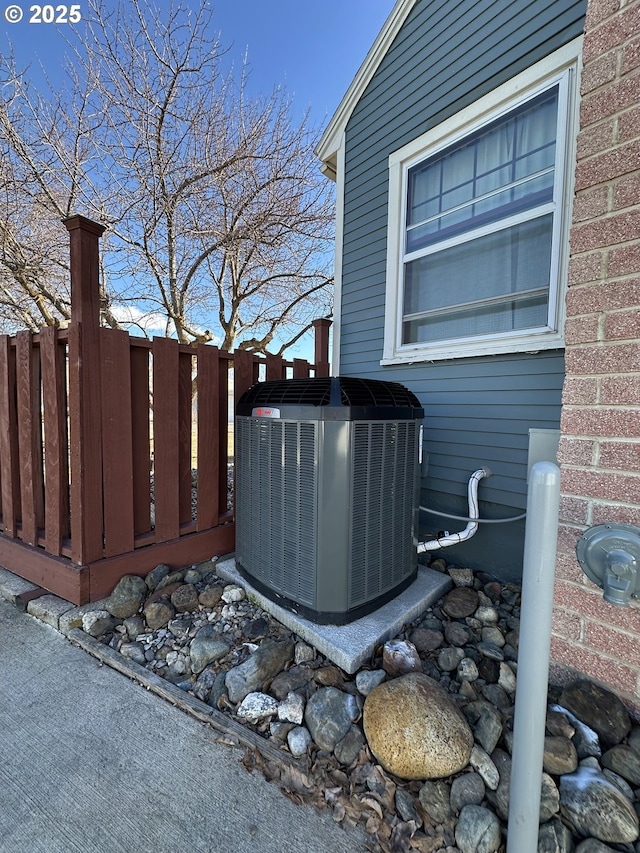 exterior space featuring fence, central AC unit, and brick siding