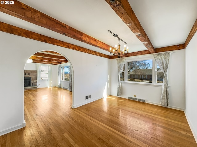 spare room with baseboards, visible vents, a chandelier, and wood finished floors