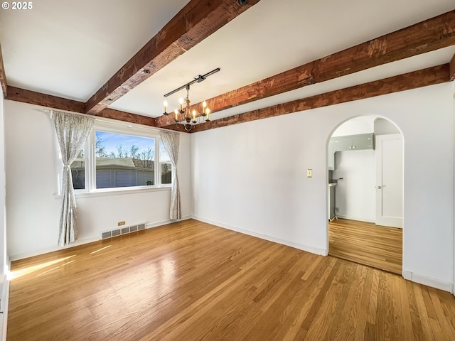 unfurnished room with baseboards, visible vents, wood finished floors, an inviting chandelier, and beam ceiling