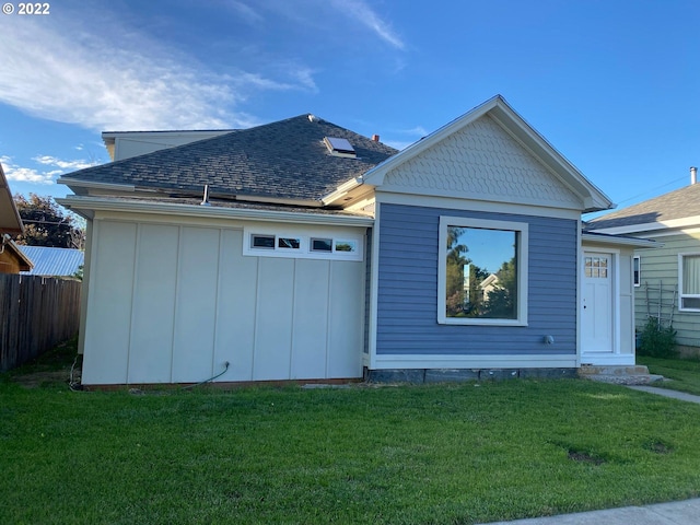 exterior space with board and batten siding, a front yard, roof with shingles, and fence