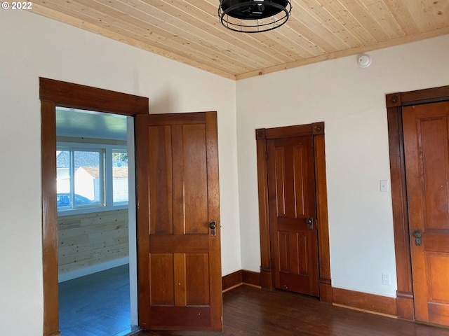 unfurnished bedroom with dark wood-style flooring, wood ceiling, and baseboards