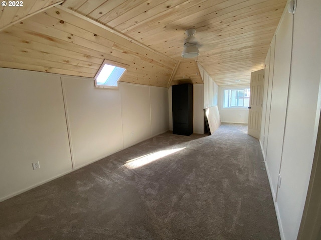additional living space with lofted ceiling, dark colored carpet, wood ceiling, and a ceiling fan