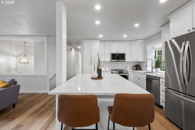 18478 Rose Ct, West Linn, OR 97068 - kitchen with appliances with stainless steel finishes, a kitchen island, recessed lighting, backsplash, and light wood-style flooring