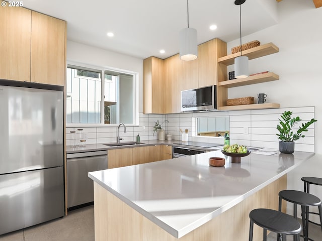 kitchen with sink, appliances with stainless steel finishes, backsplash, decorative light fixtures, and kitchen peninsula