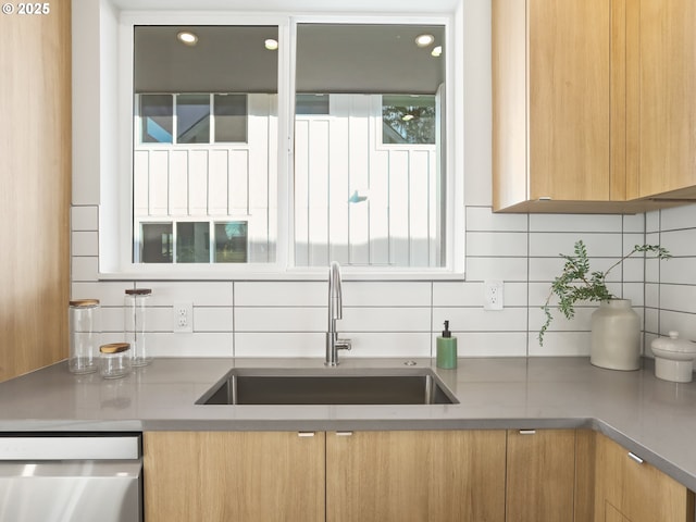 kitchen with sink, stainless steel dishwasher, and backsplash