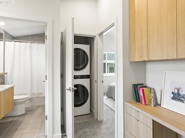 laundry area featuring light tile patterned floors and stacked washer and clothes dryer