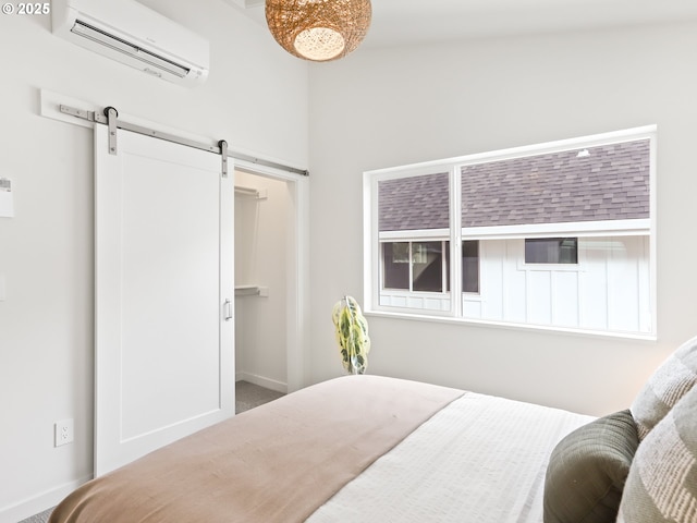 bedroom with a barn door, a wall unit AC, and a spacious closet