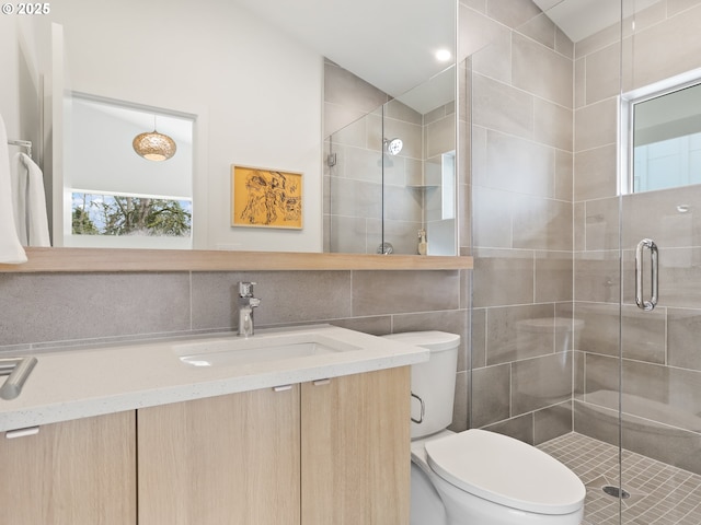 bathroom with tile walls, backsplash, vanity, an enclosed shower, and toilet