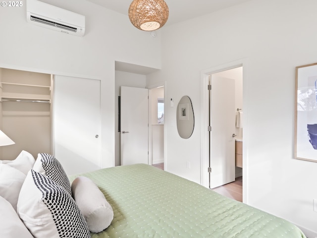 bedroom with a closet, ensuite bath, and a wall unit AC