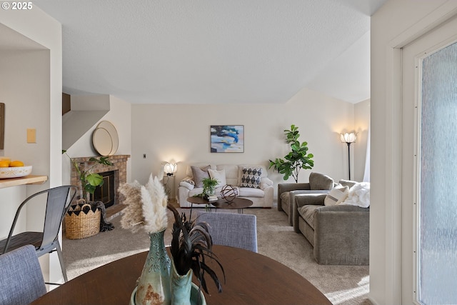 dining room with a fireplace, light colored carpet, and a textured ceiling