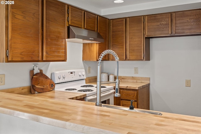 kitchen with wall chimney range hood, butcher block counters, and electric range