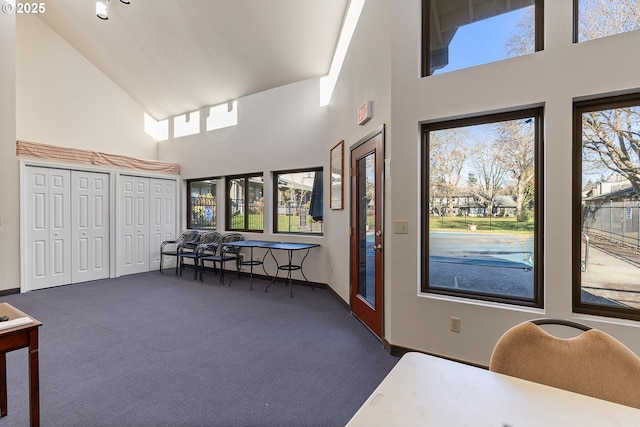 interior space featuring vaulted ceiling, dark colored carpet, and plenty of natural light