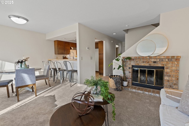 carpeted living room featuring a brick fireplace, sink, and a textured ceiling