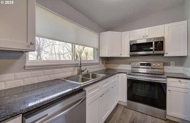 kitchen featuring appliances with stainless steel finishes, dark hardwood / wood-style floors, white cabinetry, lofted ceiling, and sink