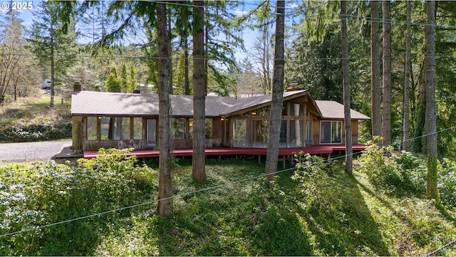 rear view of property featuring a chimney, a wooden deck, and a sunroom
