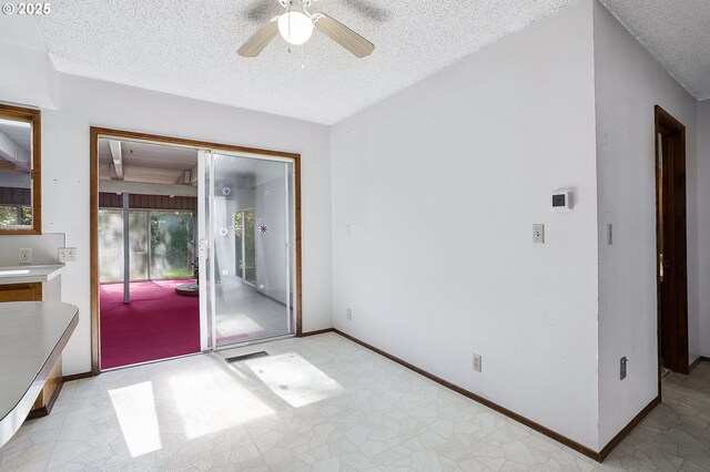 interior space with a textured ceiling, visible vents, baseboards, and ceiling fan