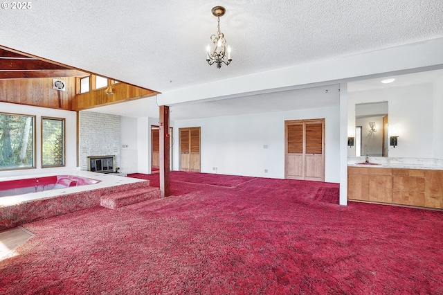 unfurnished living room featuring a brick fireplace, a textured ceiling, carpet flooring, and a sink
