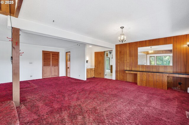 living room with a chandelier, carpet floors, a textured ceiling, and wood walls
