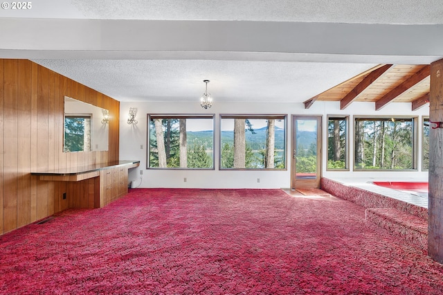 unfurnished sunroom with a chandelier and beamed ceiling