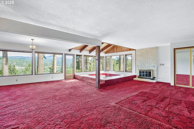 unfurnished bedroom with lofted ceiling with beams, carpet floors, a textured ceiling, and a fireplace
