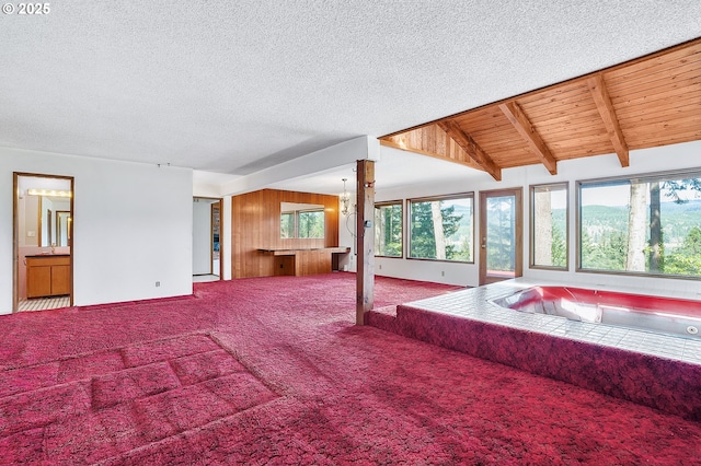 carpeted living area with a textured ceiling and vaulted ceiling with beams