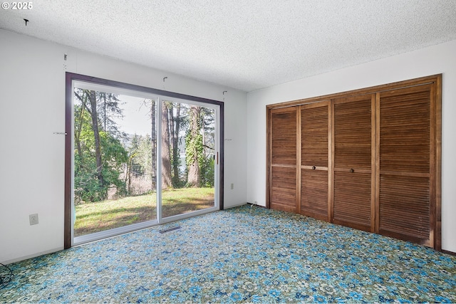 unfurnished bedroom with a textured ceiling, carpet flooring, and access to outside