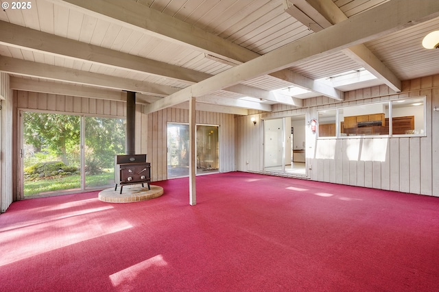 interior space featuring wood walls, carpet, and a wood stove