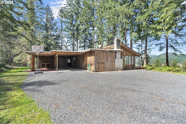 exterior space featuring gravel driveway, a mountain view, and a carport