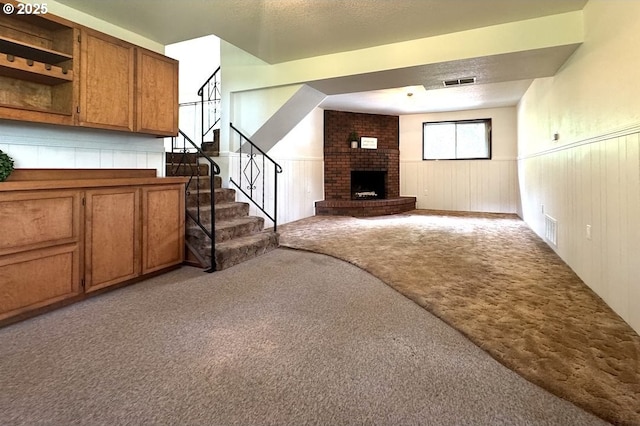 unfurnished living room featuring carpet, wainscoting, and visible vents