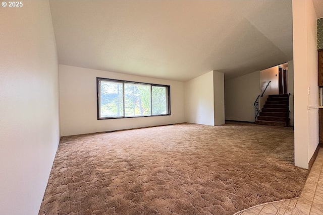 unfurnished living room with carpet flooring, lofted ceiling, and stairway