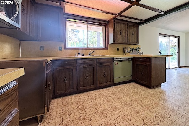 kitchen featuring light countertops, stainless steel microwave, a peninsula, and dishwasher